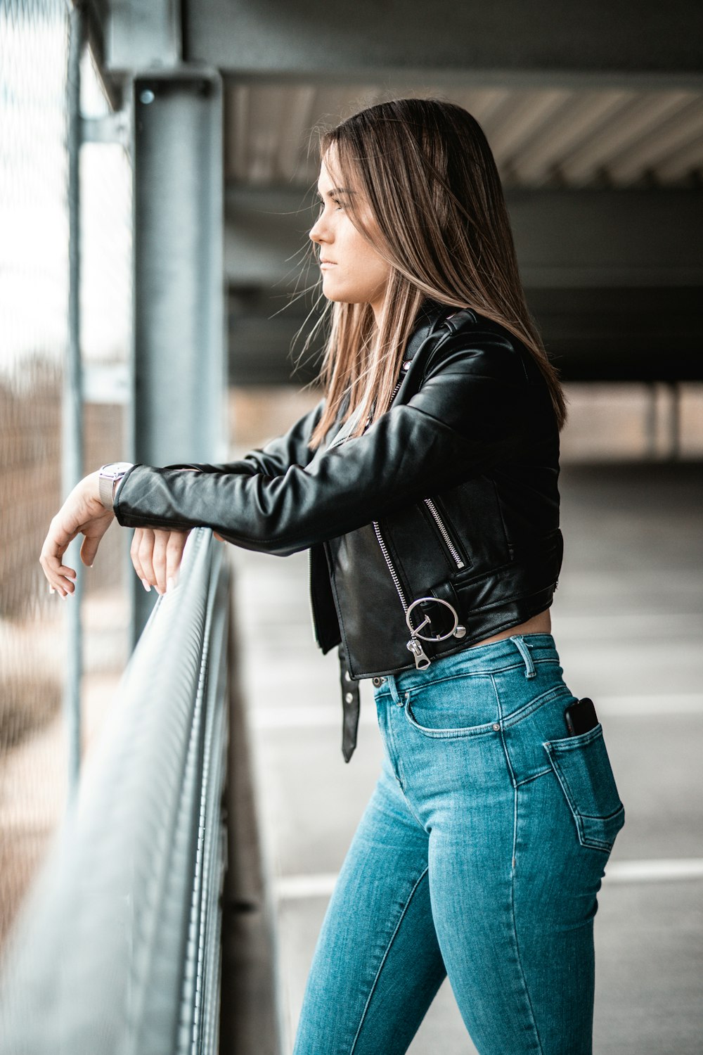 Woman in black leather jacket and blue denim jeans leaning on gray metal  railings photo – Free Grey Image on Unsplash