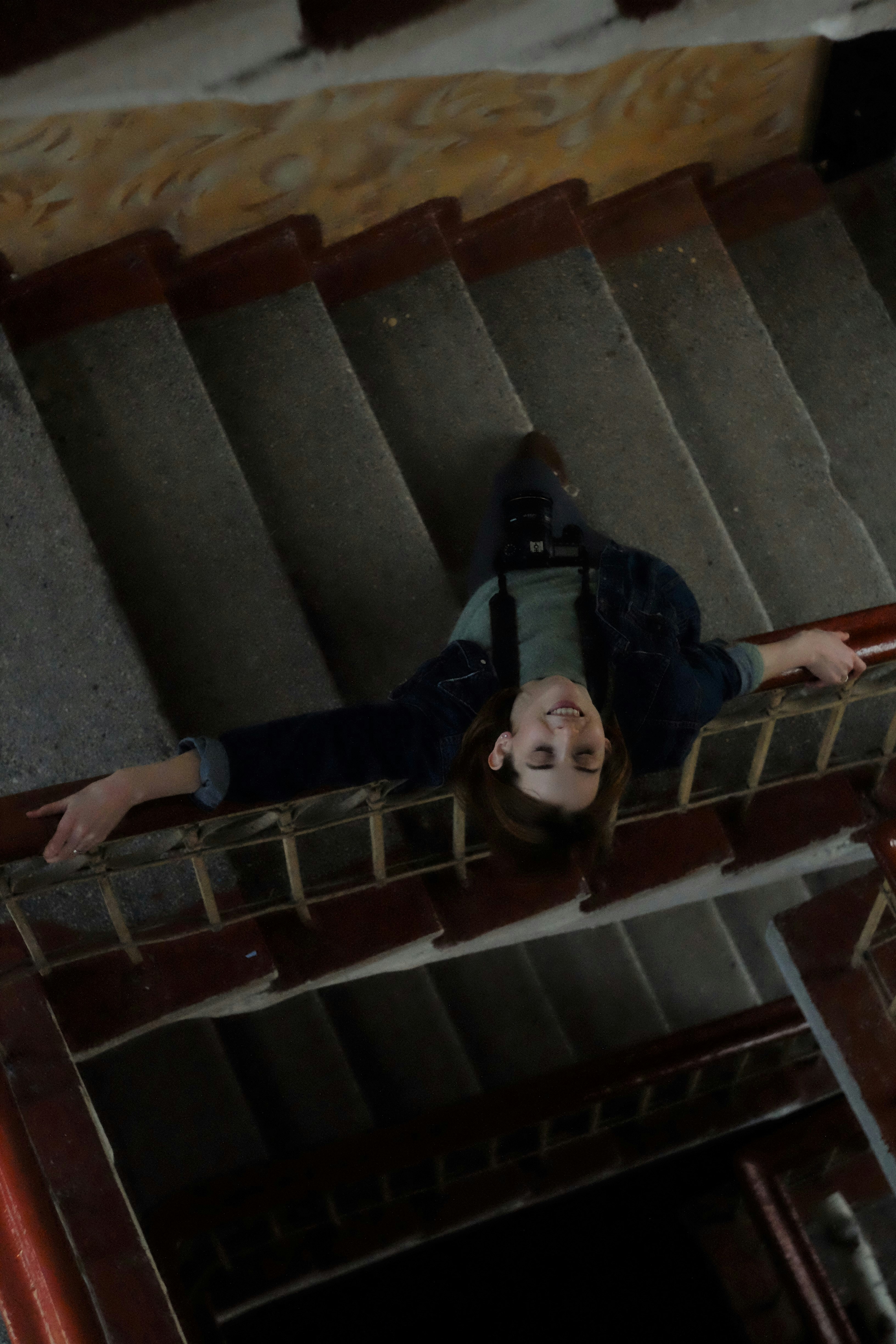 man in black jacket lying on brown wooden staircase