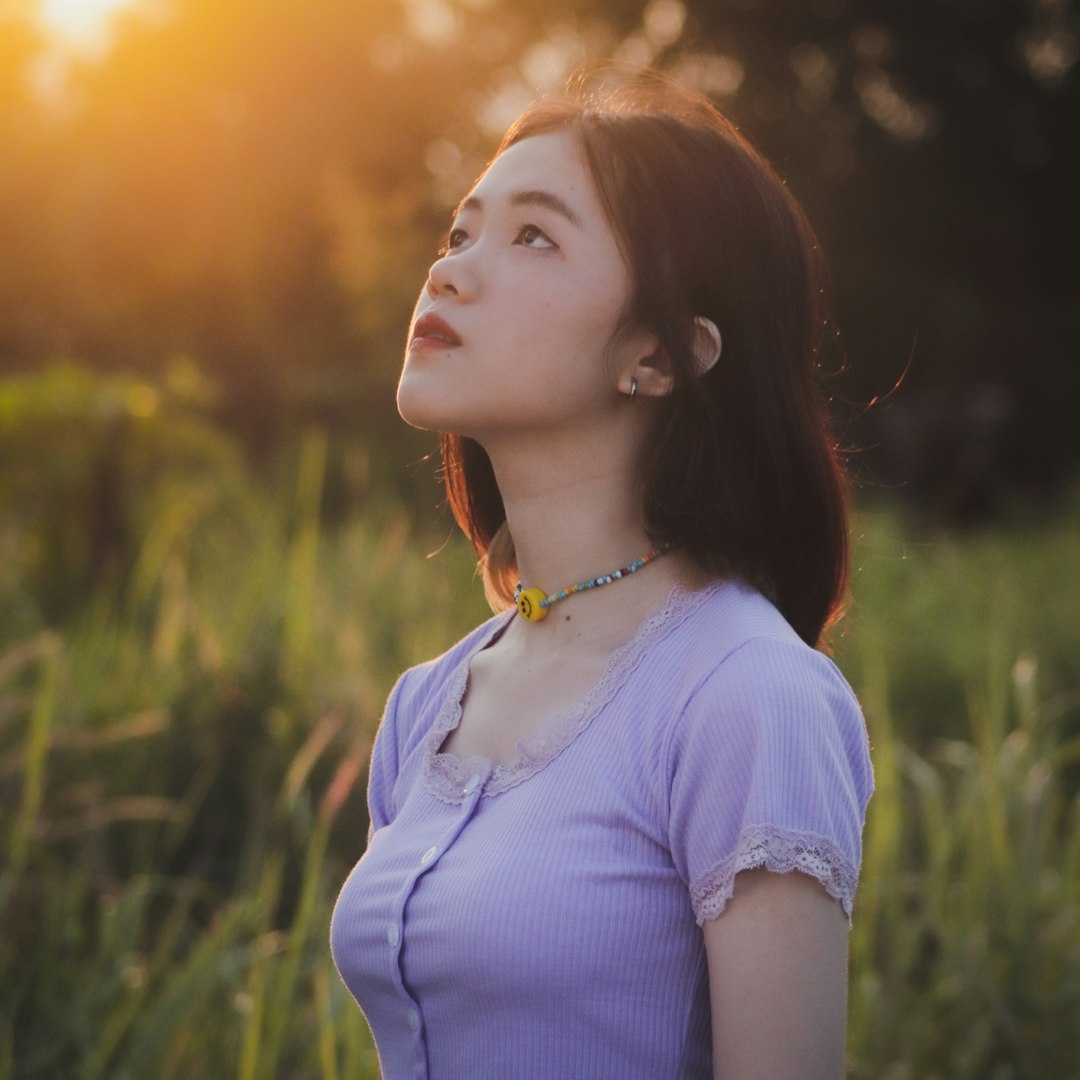 woman in white shirt standing on green grass field during sunset