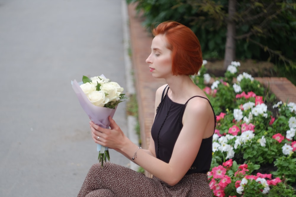 woman in black tank top holding bouquet of flowers
