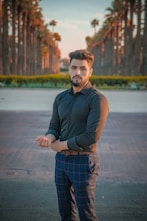 man in black polo shirt and blue and white plaid pants standing on gray concrete floor