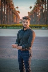 man in black polo shirt and blue and white plaid pants standing on gray concrete floor