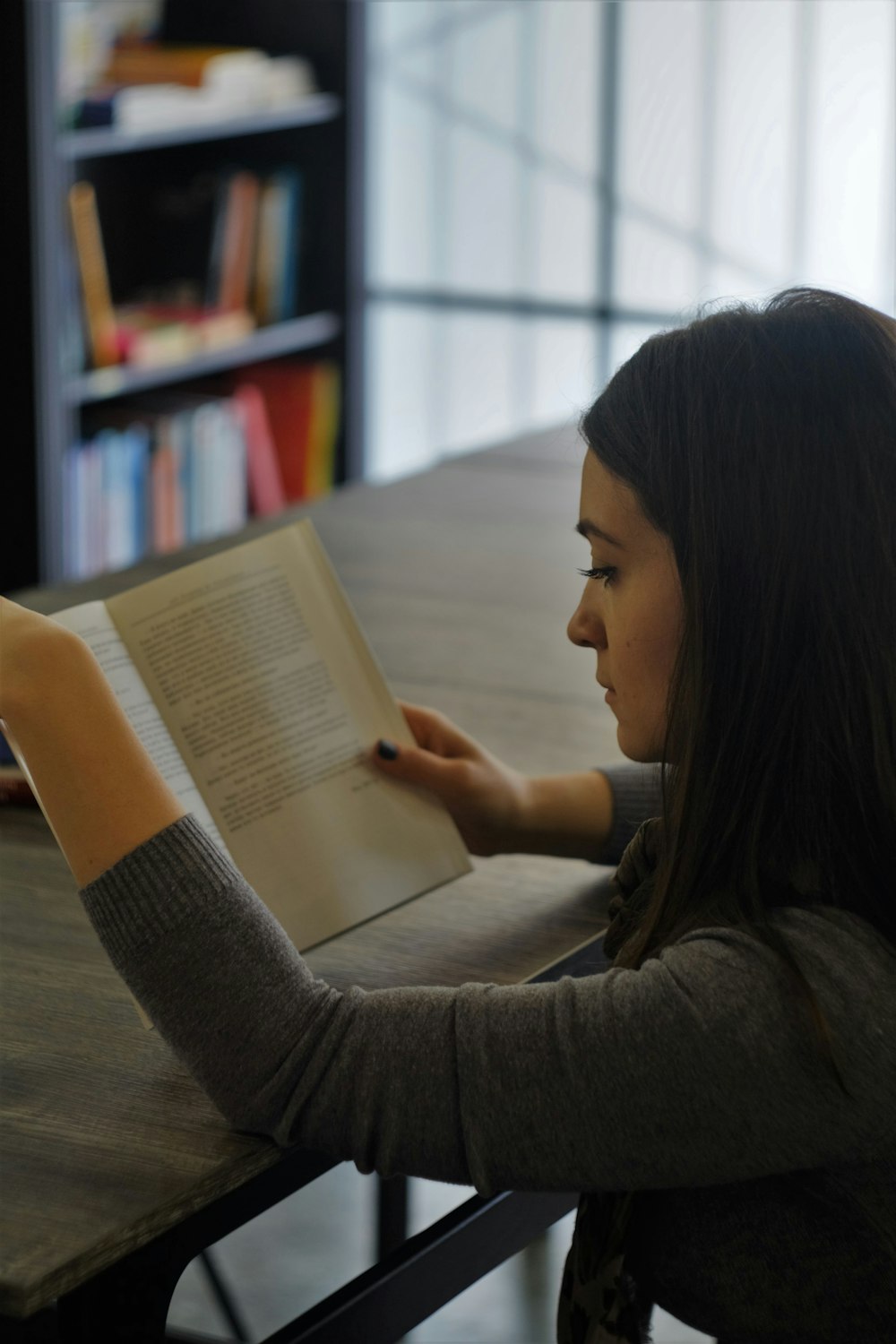 mujer con camiseta gris leyendo libro