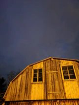 A welcoming barn entrance bathed in warm afternoon light with horses visible nearby.