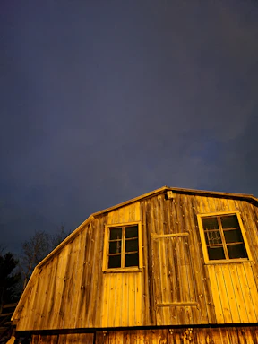 A welcoming barn entrance bathed in warm afternoon light with horses visible nearby.