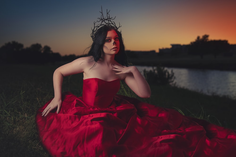 woman in red tube dress sitting on rock during sunset