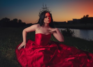 woman in red tube dress sitting on rock during sunset