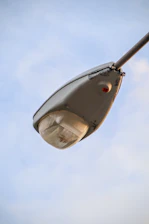 Close-up of a parking lot light fixture being repaired under a clear evening sky.
