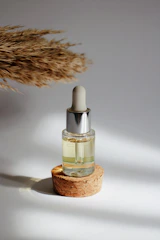 Elegant dropper bottle of Elixir Capilar serum with castor oil and quinine roots in the background.