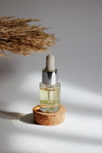 Image of a small amber bottle with a dropper, surrounded by fresh herbs and traditional woven basket.