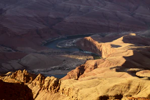 Wide shot of the canyon landscape with the river winding through and the glamping tents blending into nature.