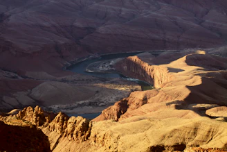 Wide shot of the canyon landscape with the river winding through and the glamping tents blending into nature.