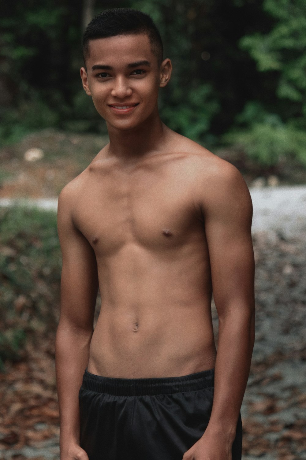 topless boy smiling near green grass during daytime