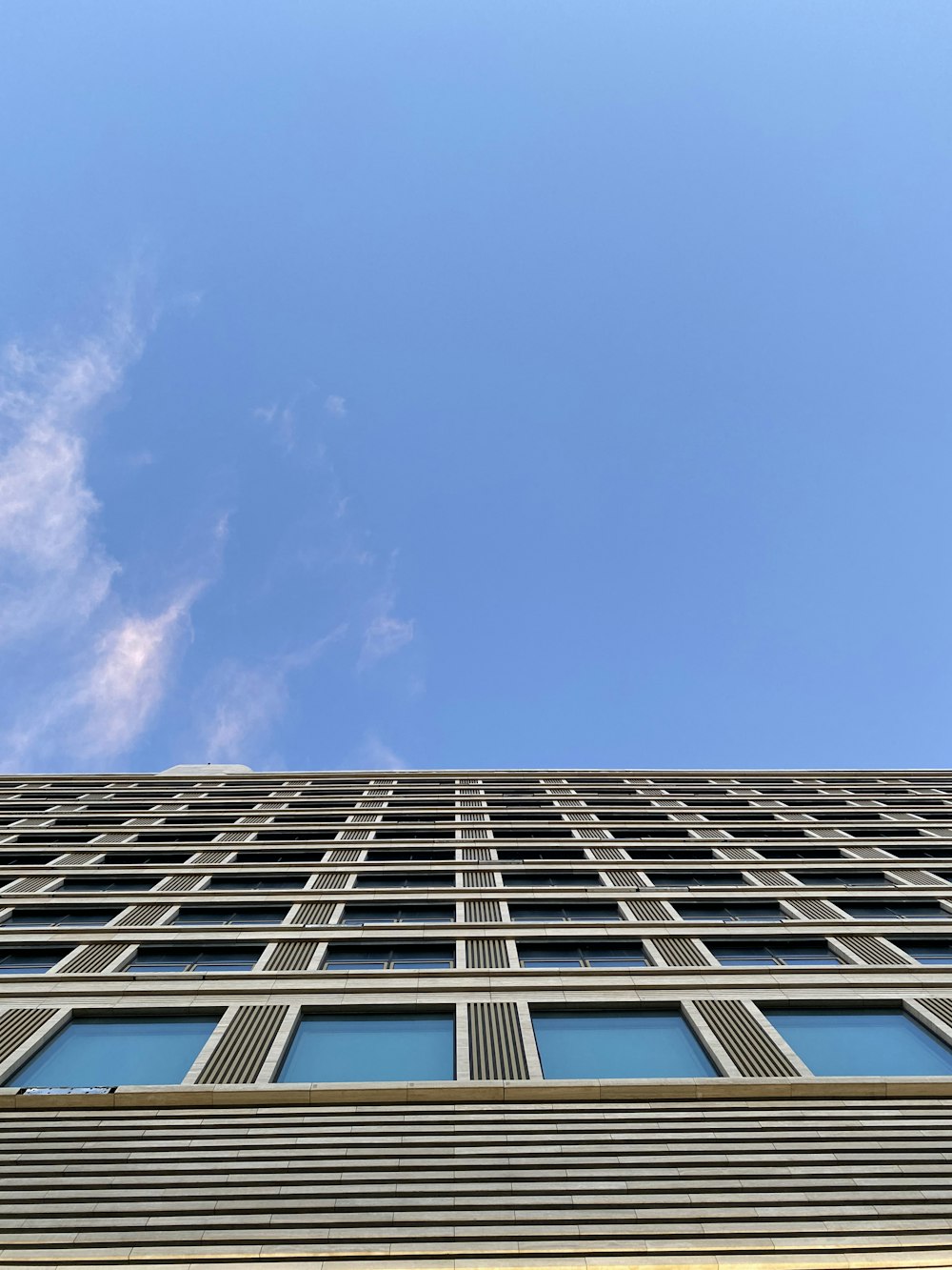 Weißer und blau bewölkter Himmel über weißem Betongebäude