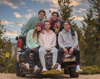 3 women sitting on brown wooden bench during daytime