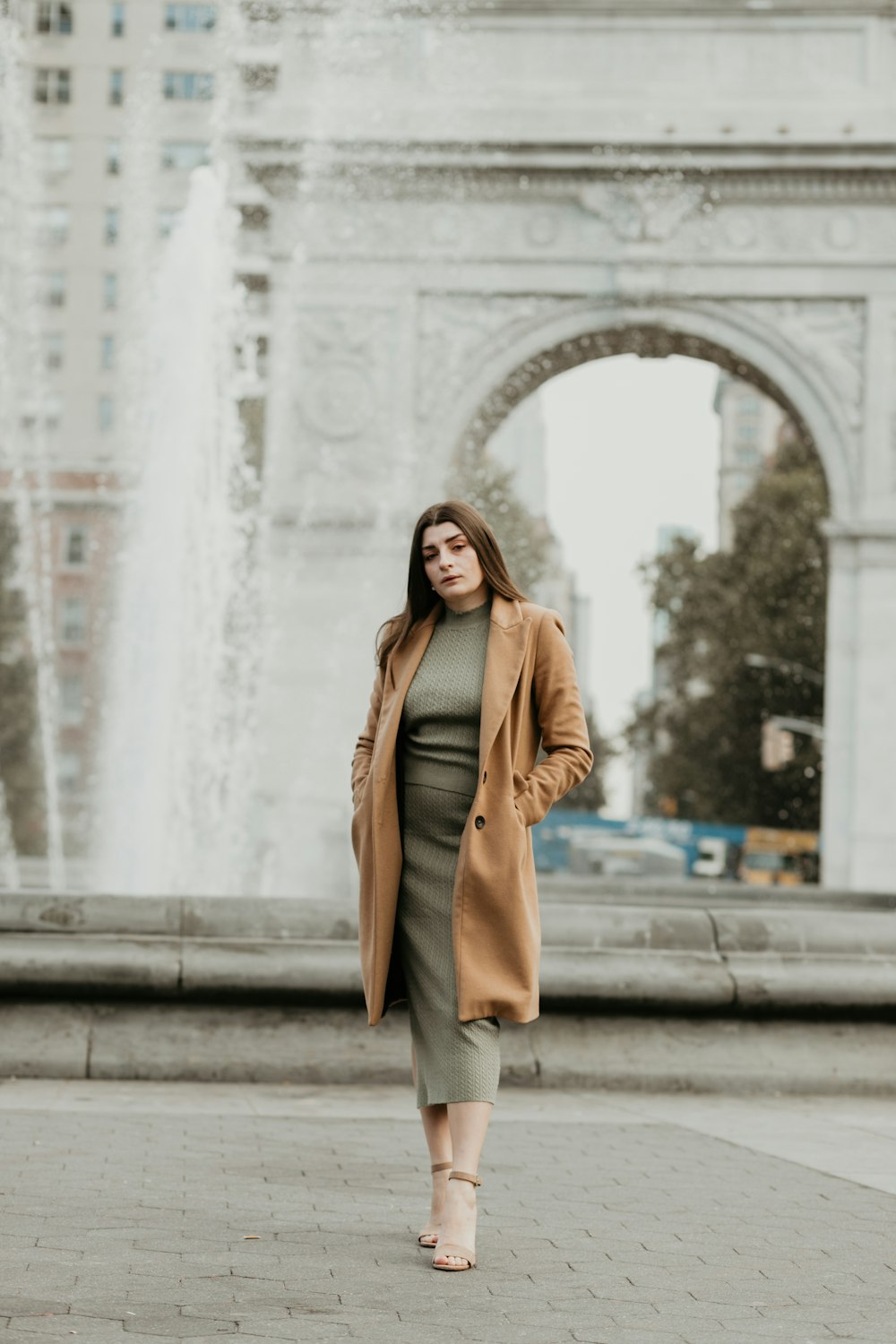 woman in brown coat standing on gray concrete stairs during daytime