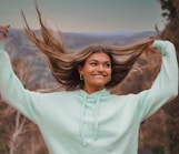 woman in white long sleeve shirt standing on brown grass field during daytime