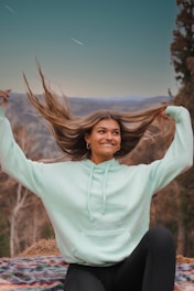 woman in white long sleeve hoodie sitting on brown grass field during daytime