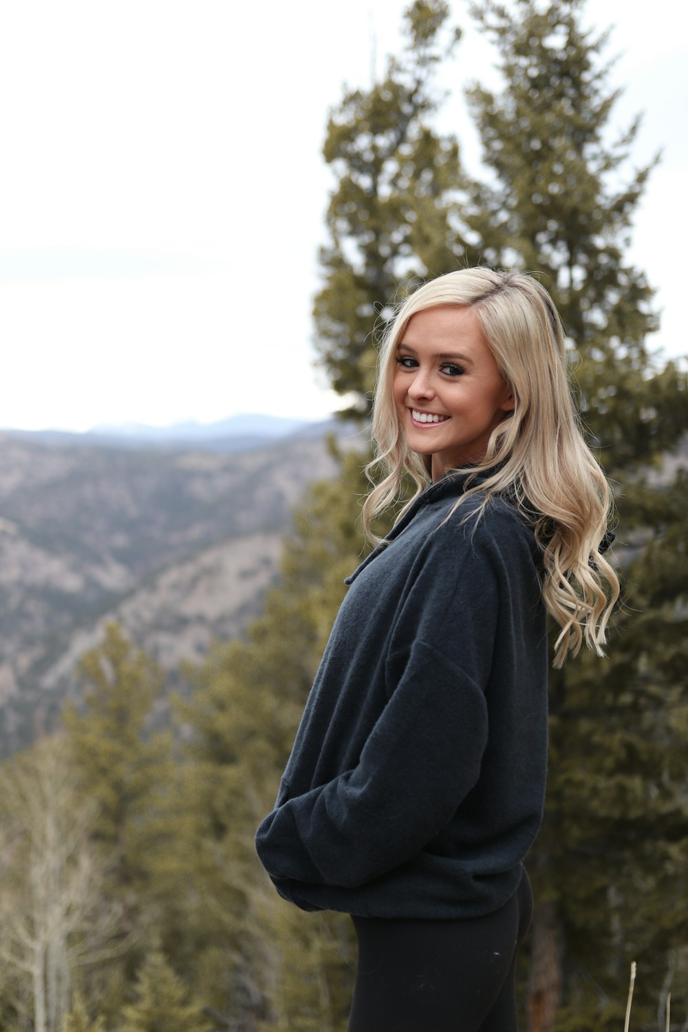 woman in black jacket standing near green trees during daytime