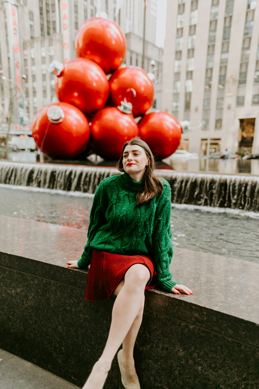 woman in green long sleeve shirt sitting on brown wooden bench holding red baubles