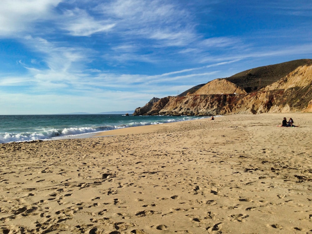 brown sand beach near brown mountain under blue sky during daytime