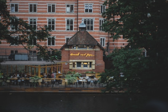 A cozy café terrace overlooking a scenic urban park with people enjoying their time.