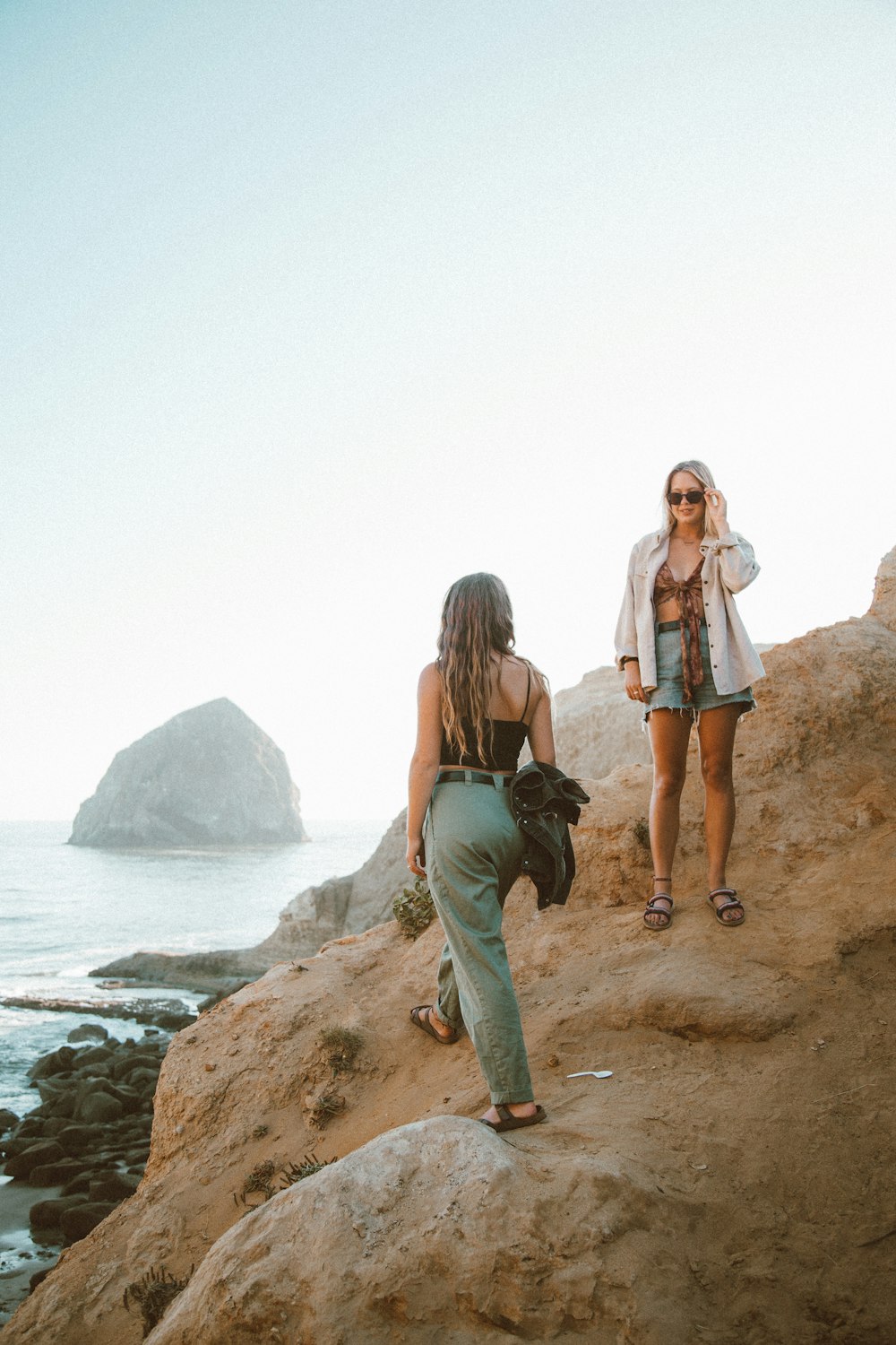 woman in blue denim jacket standing beside woman in blue denim jacket on brown rock formation