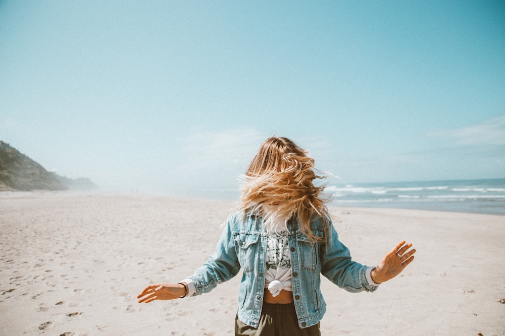 girl in blue denim jacket standing on beach during daytime