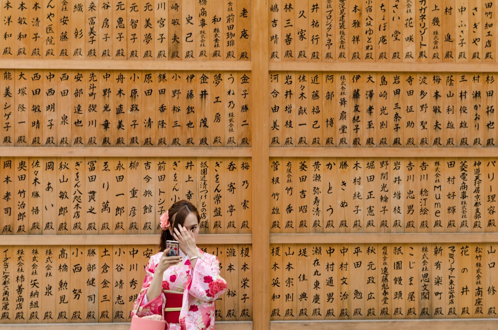 girl in pink and white floral dress covering her face with her hands