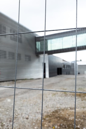 A sleek steel fence surrounding a modern office building under a clear blue sky.