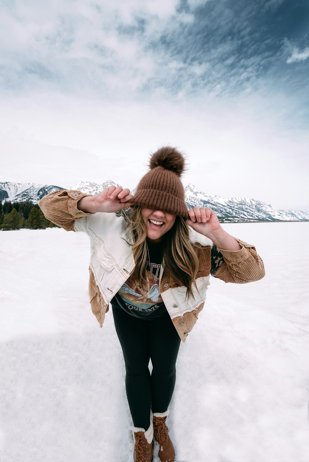 woman in brown parka jacket standing on snow covered ground during daytime