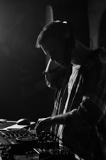 A close-up of a DJ mixing music on a turntable with headphones and a focused expression.