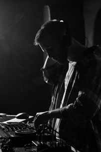 A close-up of a DJ mixing music on a turntable with headphones and a focused expression.