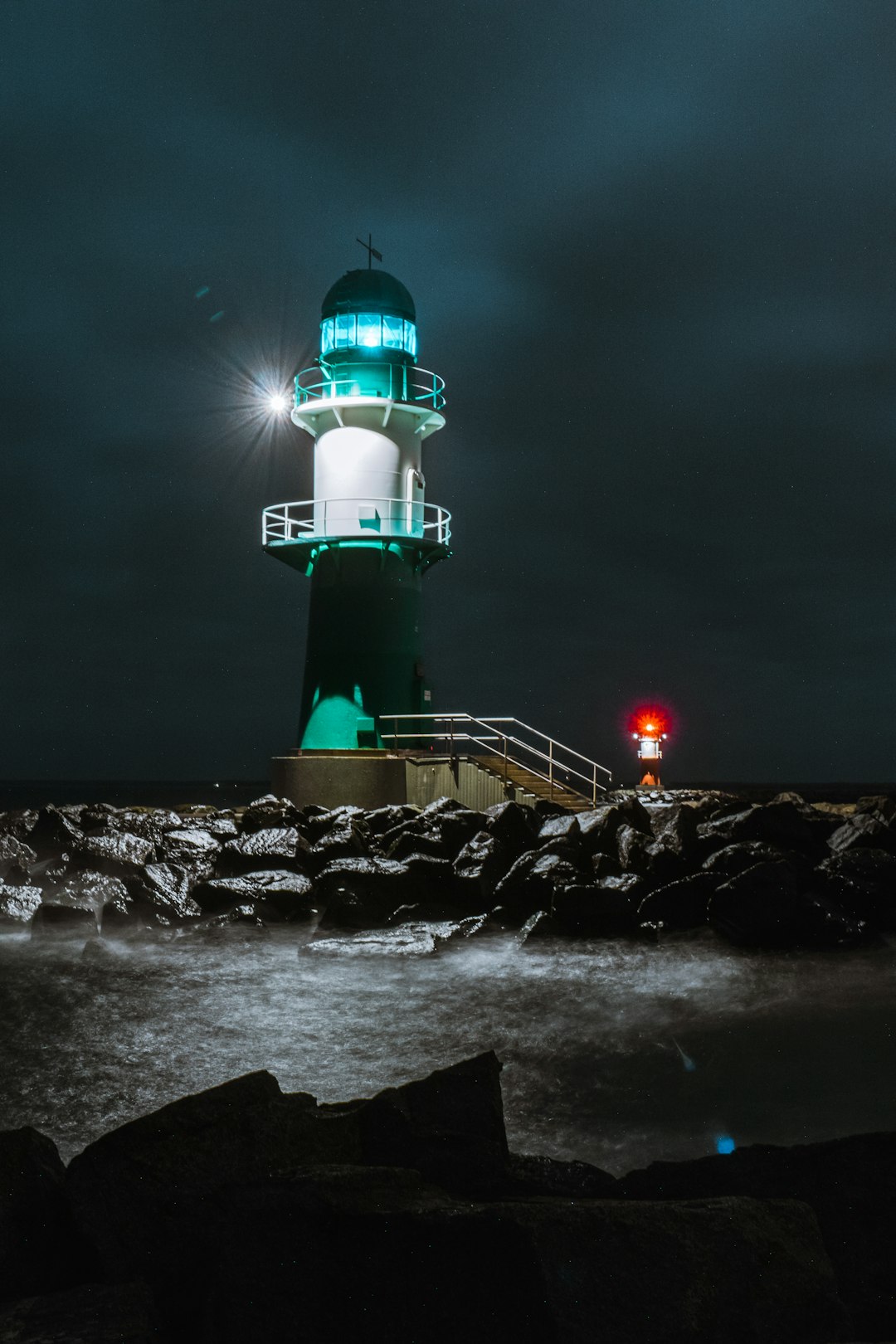 white and green lighthouse on rocky shore during night time