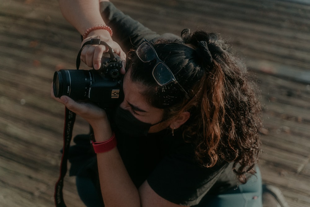 woman in black t-shirt holding black dslr camera