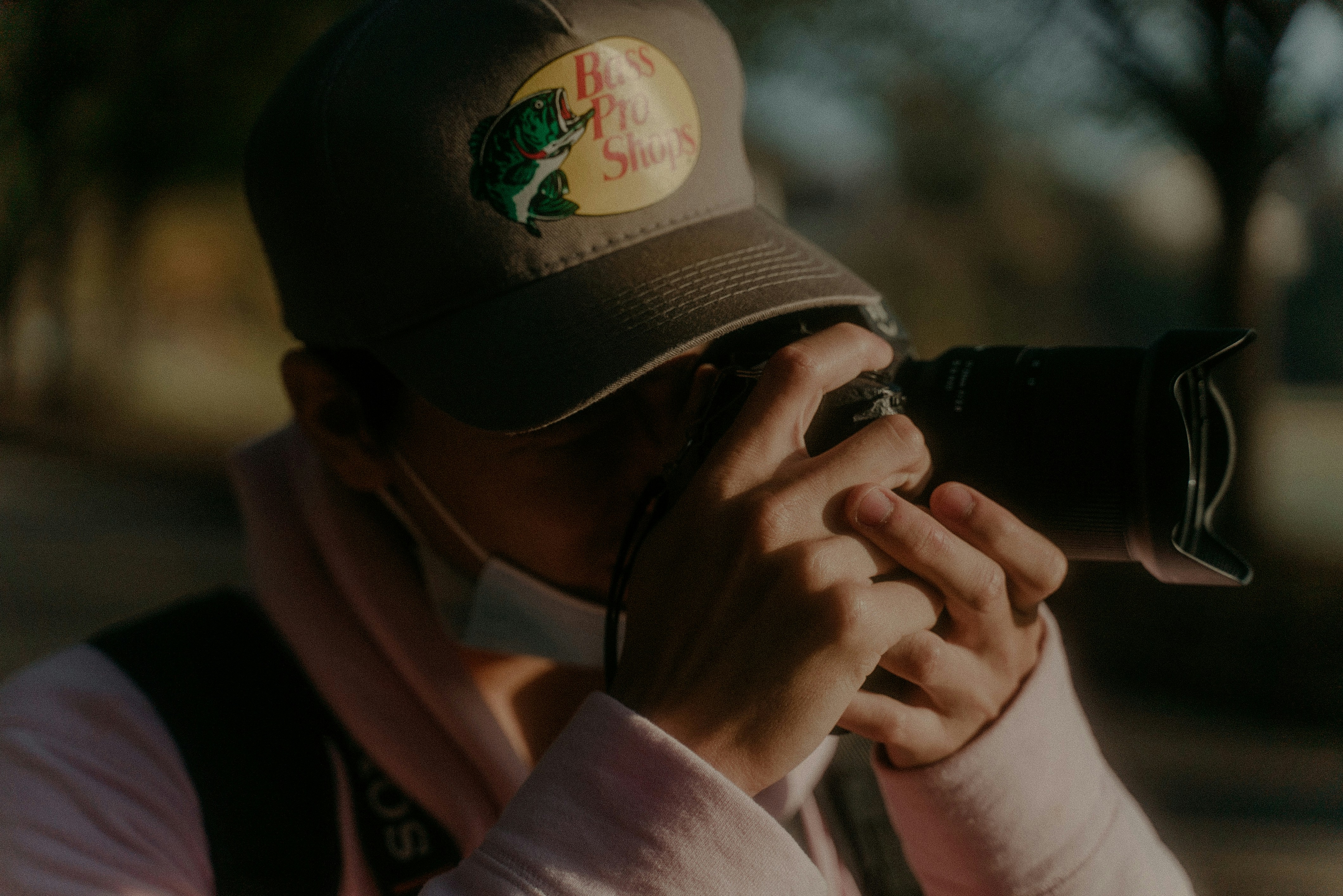 man in white long sleeve shirt and black cap holding black dslr camera