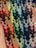 A collection of colorful, intricately woven friendship bracelets featuring geometric patterns. The designs incorporate a variety of colors, arranged in a repeating zigzag pattern, showcased against a person's palm, highlighting the handmade nature of the items.