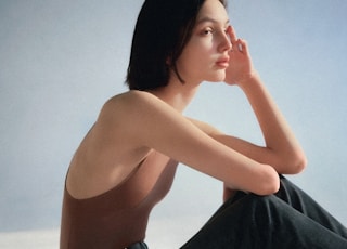 woman in black pants sitting on white sand during daytime