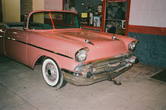 A bright neon pink convertible parked under glowing space-themed streetlights at dusk.