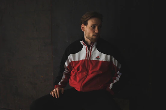 man in black white and red long sleeve shirt sitting on black chair