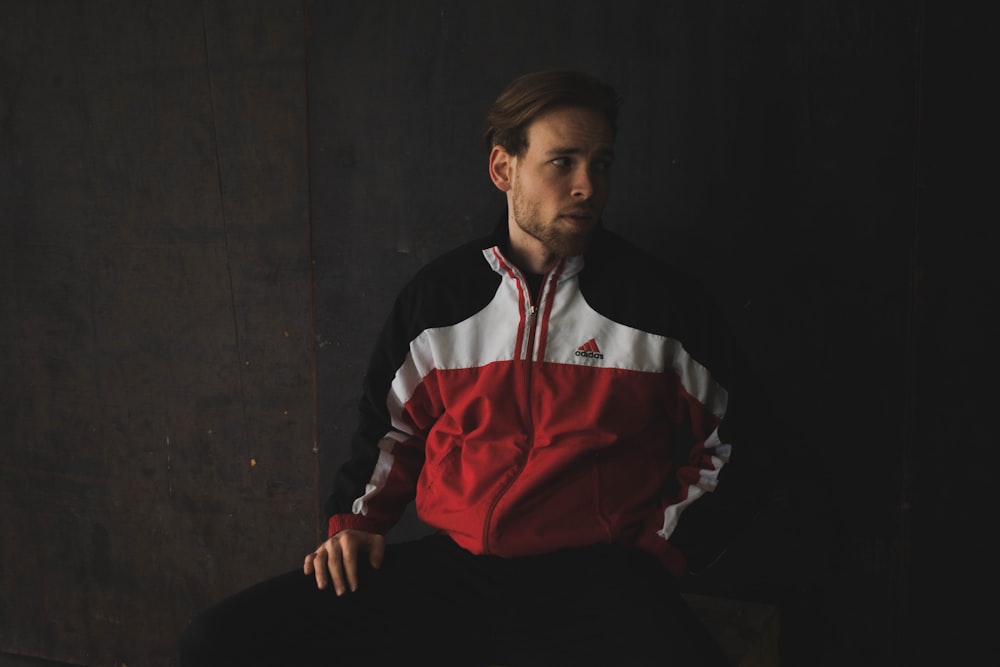 man in black white and red long sleeve shirt sitting on black chair