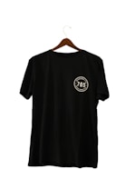 A black T-shirt hanging on a wooden hanger, featuring a circular emblem with the number '705' and the words 'seven zero five' twice around it.