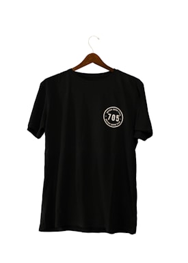 A black T-shirt hanging on a wooden hanger, featuring a circular emblem with the number '705' and the words 'seven zero five' twice around it.