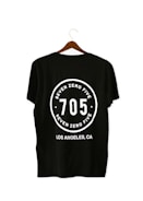 A black T-shirt is displayed on a wooden hanger with a bold white print on the back. The print includes the numbers '705' in large font, encased within a circular design. Above and below the numbers, the words 'SEVEN ZERO FIVE' and 'LOS ANGELES, CA' are printed respectively.