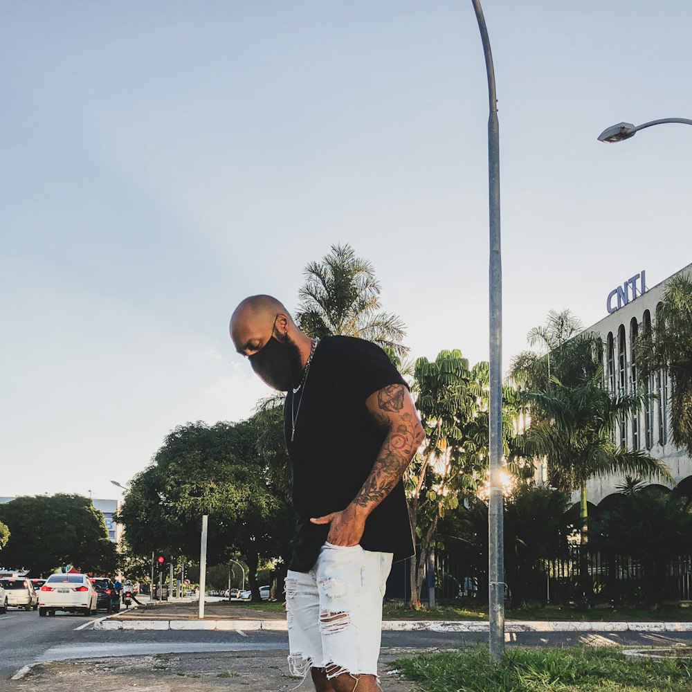 man in black t-shirt and white shorts standing on basketball court during daytime