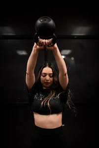 A focused personal trainer guiding a client through a kettlebell swing in a vibrant CrossFit gym.
