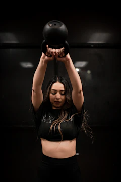 Athlete doing high-intensity interval training with kettlebells in a dimly lit gym space.