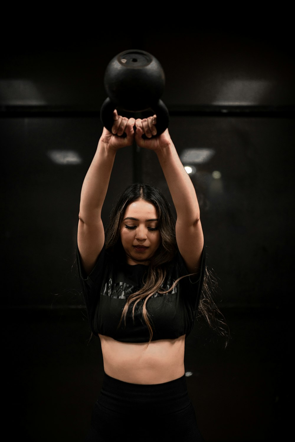 donna in reggiseno sportivo nero e mutandine che tengono kettlebell nero