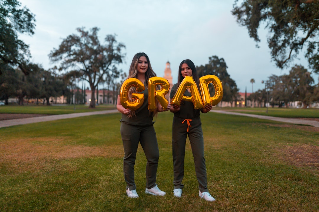 woman in black pants holding gold and black football, Best Friends Graduation Shoot