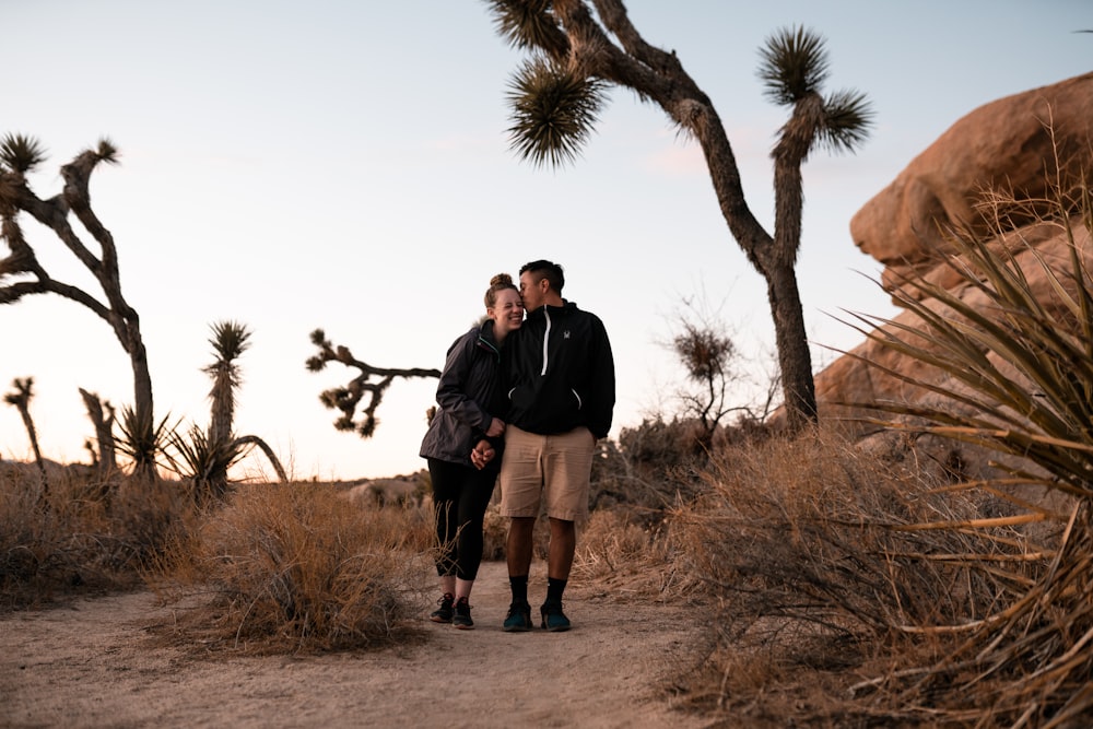 man and woman standing on brown dirt road during daytime